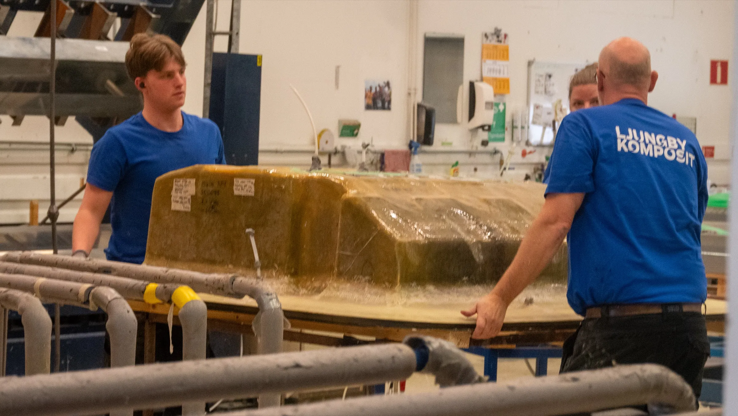 Three colleagues lifting a large mould together in production